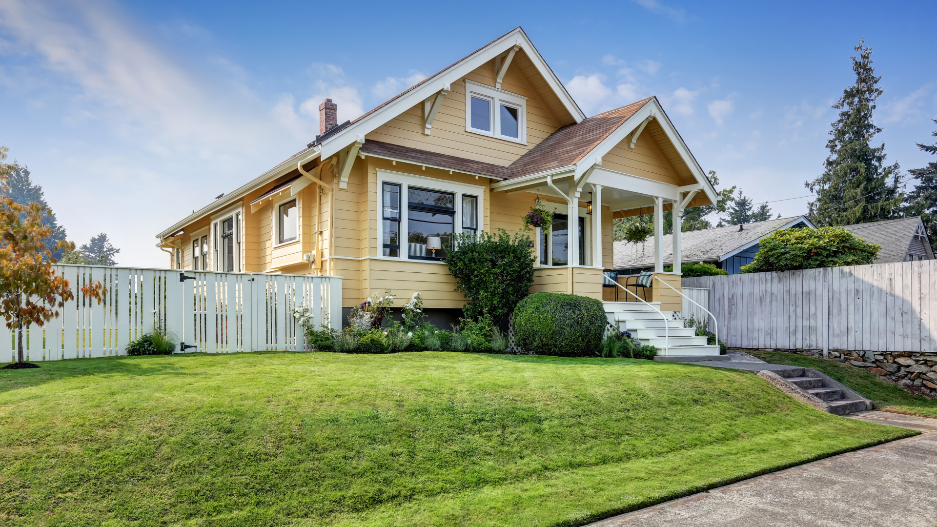 A yellow house with a white fence in front of it